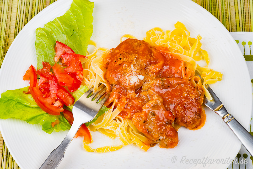 Fläskfilé i skivor lagad i tomatsås och toppad med parmesan på tallrik Fläskfilé i skivor lagad i tomatsås och toppad med parmesan på tallrik
