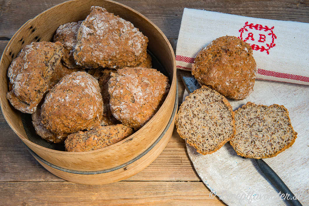 Nybakta gluten- och laktosfria frukostbullar i brödkorg samt uppskurna i halvor