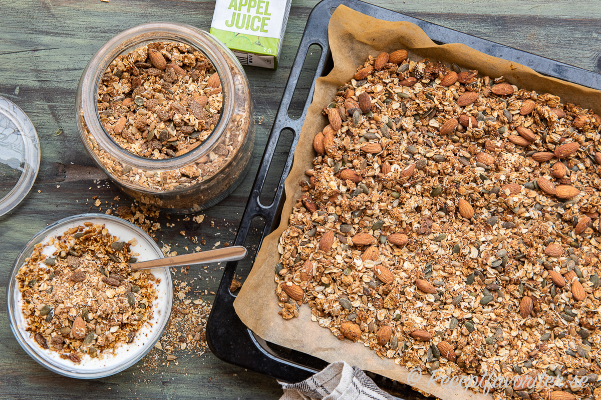 Granola med äppeljuice i burk, i frukostskål samt på ugnsplåt. Granola med äppeljuice i burk, i frukostskål samt på ugnsplåt.