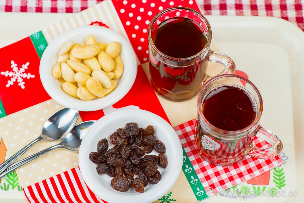 Hemjäst glögg serverad i glögg-glas med skållad mandel och russin Hemjäst glögg serverad i glögg-glas med skållad mandel och russin
