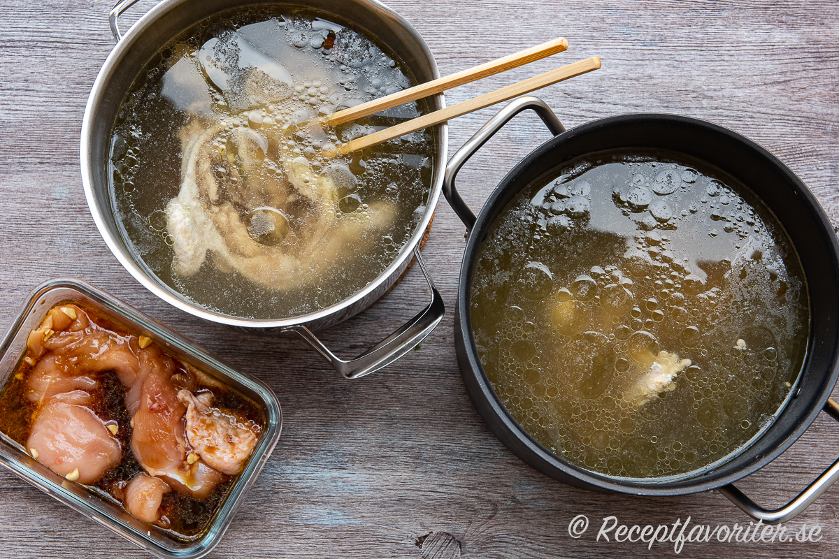 Två kastruller kycklingbuljong till ramen med kycklingköttet urplockat vid sidan. Två kastruller kycklingbuljong till ramen med kycklingköttet urplockat vid sidan.