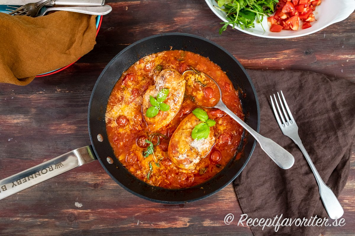 Kycklingfiléerna bryns först och får puttra klart i en smakrik tomatsås som toppas med parmesan, färsk basilika och rosmarin. 