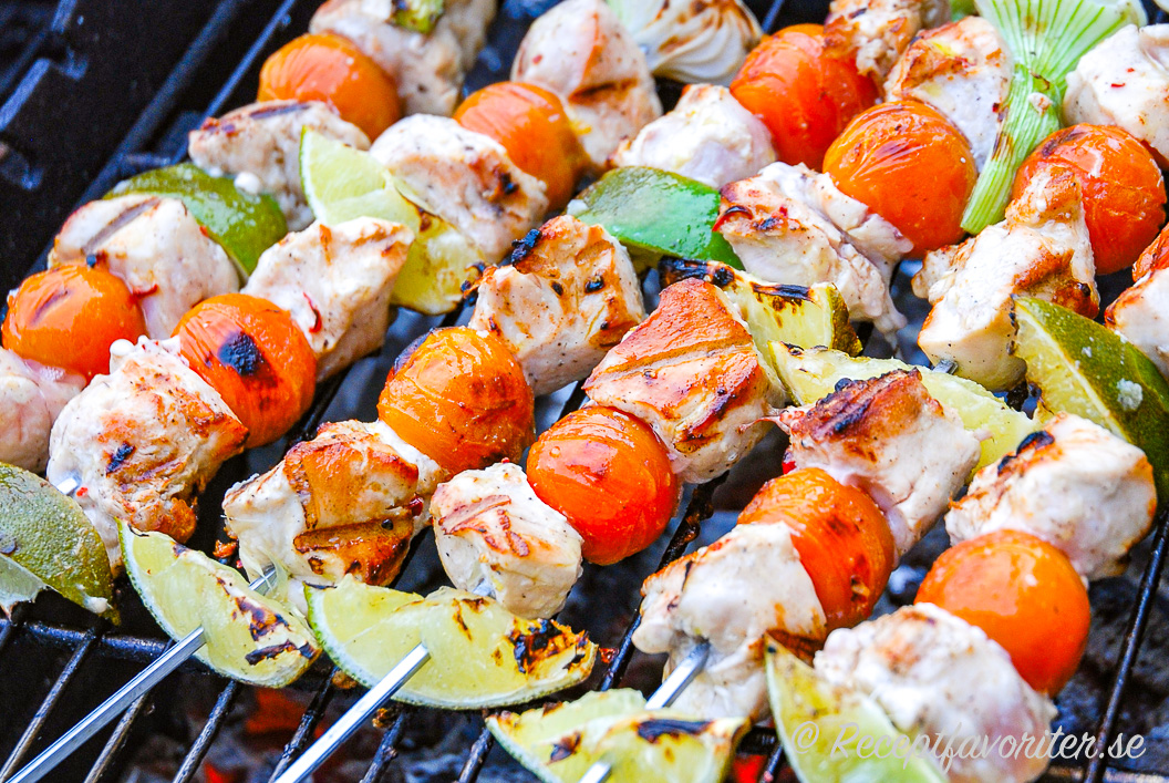 Grillspett med kycklingfilé, färsk lime, knipplök och cocktailtomater på grillen. Grillspett med kycklingfilé, färsk lime, knipplök och cocktailtomater på grillen.