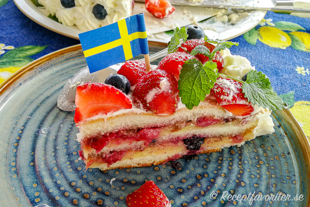 En bit midsommartårta med färska jordgubbar och blåbär och massor av god fyllning av vaniljkräm och mosade bär. En bit midsommartårta med färska jordgubbar och blåbär och massor av god fyllning av vaniljkräm och mosade bär.