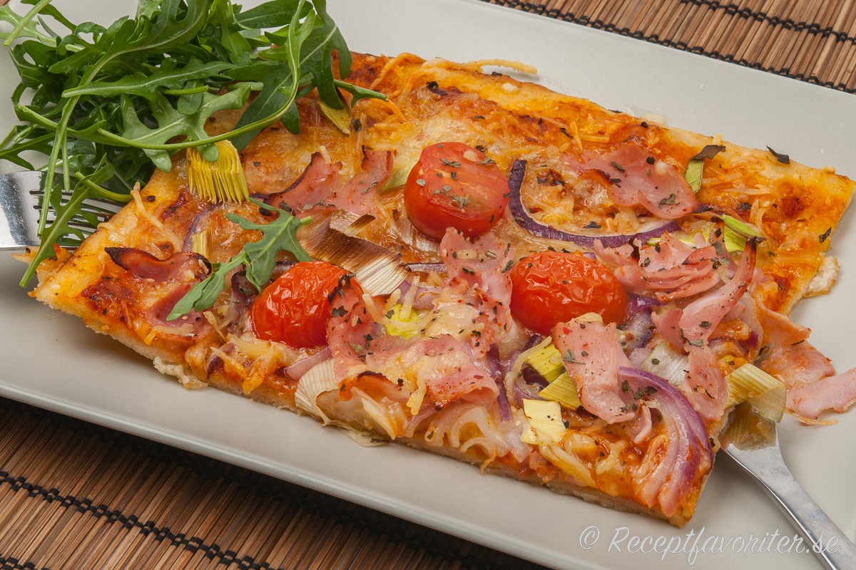 Pizzan kan du toppa med valfria pålägg - här med rökt skinka, strimlad purjolök, rödlök och delade coccktailtomater. 