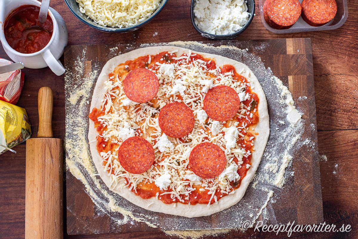 Pizzabottnen toppas med tomatsås, riven mozzarella, färsk mozzarella i bitar samt de toppings du önskar. Ovan skivor av pepperoni - salami korv. 