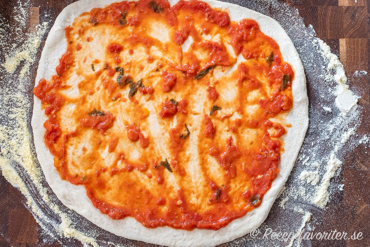Pizzasåsen breds ut på pizzabottnen. 