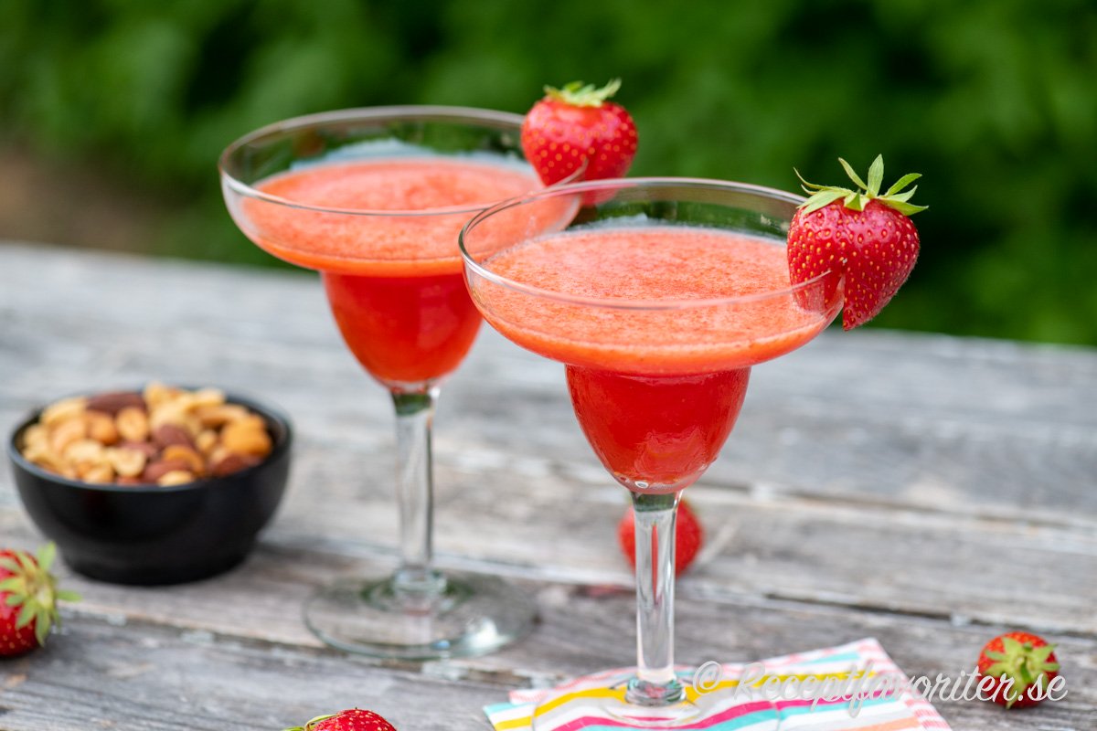Två cocktail med läskande fryst jordgubbsdaiquiri med jordgubbe som garnering.  