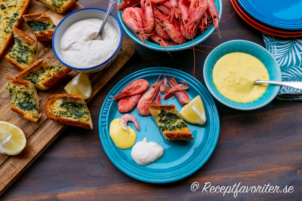 Räkor på tallrik med två såser - het dippsås och aioli vitlöksmajonnäs, vitlöksbröd och citron på tallrik. Räkor på tallrik med två såser - het dippsås och aioli vitlöksmajonnäs, vitlöksbröd och citron på tallrik.