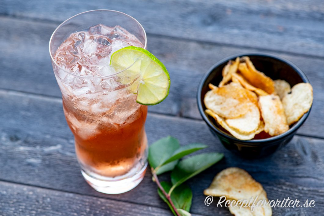 Vodka Cranberry i highballglas med is och lime serverad med lantchips. 