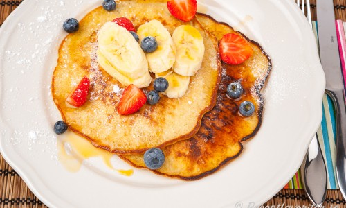 Amerikanska pannkakor med banan i smeten på tallrik med tillbehör. 