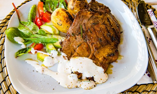 Grillad fläskkarré med rostad potatis samt tillbehör på tallrik